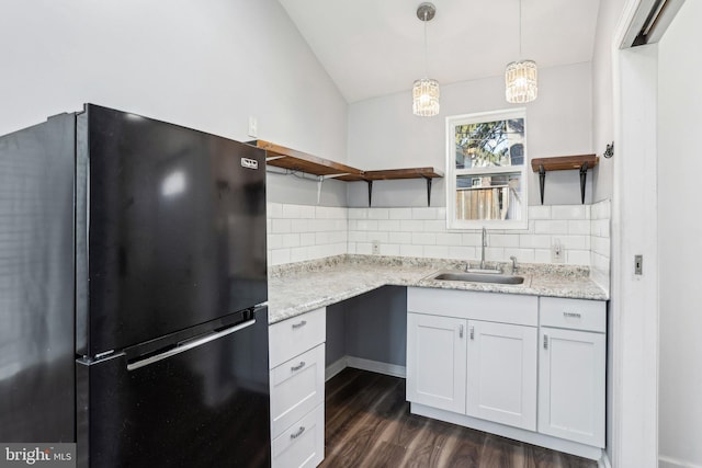 kitchen featuring freestanding refrigerator, a sink, decorative backsplash, and open shelves