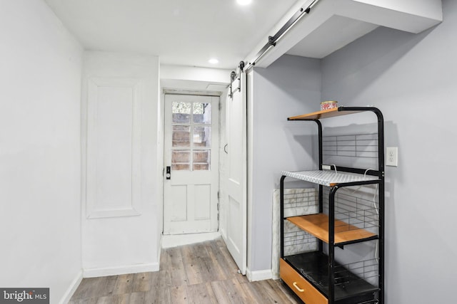 doorway featuring wood finished floors, baseboards, and a barn door