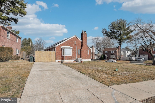 view of front of property featuring brick siding, a chimney, and a front yard