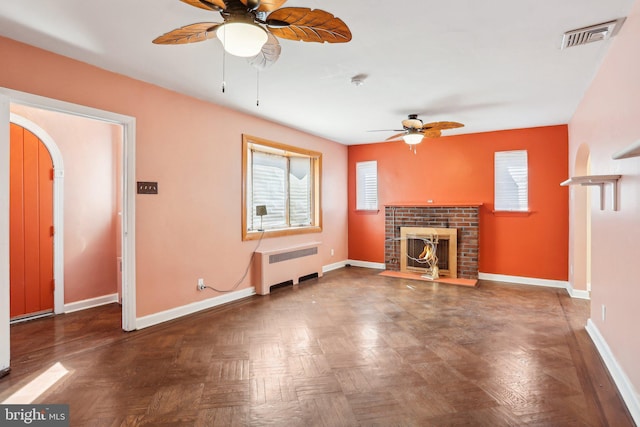 unfurnished living room with arched walkways, a fireplace, visible vents, radiator heating unit, and baseboards