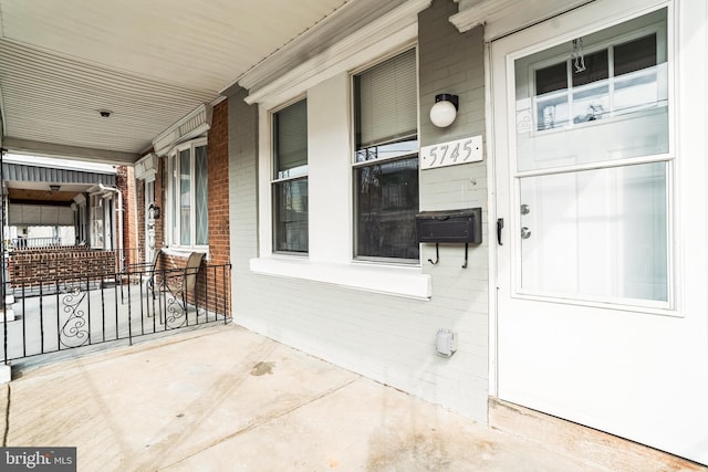 doorway to property with covered porch and brick siding