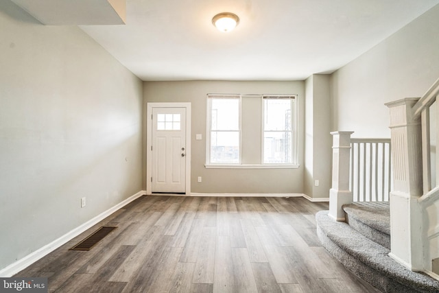 entrance foyer featuring baseboards, stairs, visible vents, and wood finished floors