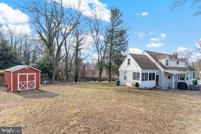 view of yard featuring an outdoor structure, central air condition unit, a storage unit, and a sunroom