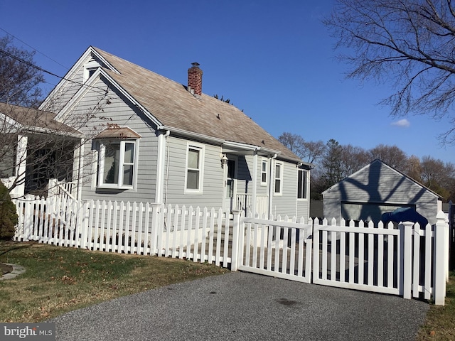 view of front of property with a fenced front yard, a shingled roof, and a chimney