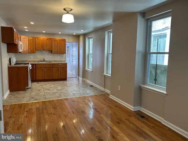 kitchen featuring white range with electric cooktop, visible vents, light countertops, brown cabinetry, and stainless steel microwave