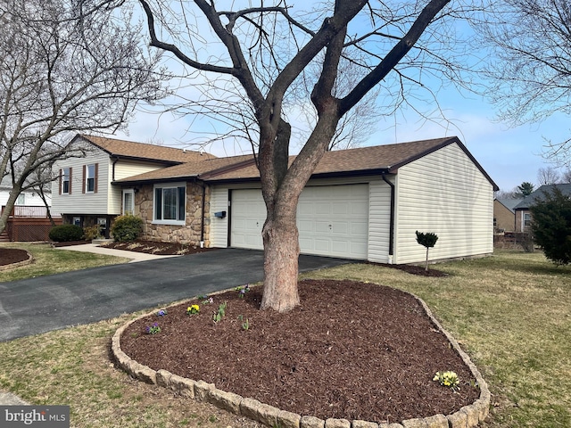 tri-level home featuring a shingled roof, a front yard, a garage, stone siding, and driveway