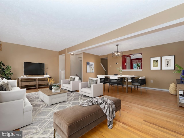 living area featuring a chandelier, light wood-type flooring, and baseboards