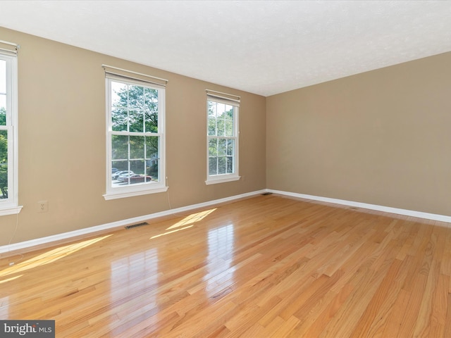 empty room featuring visible vents, light wood-style flooring, and baseboards