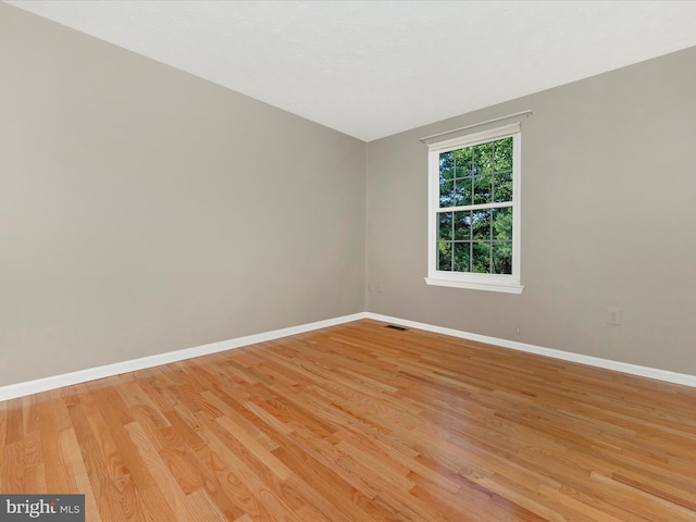 spare room featuring light wood-type flooring, baseboards, and visible vents