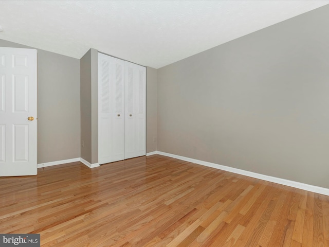 unfurnished bedroom featuring a closet, light wood-style flooring, and baseboards