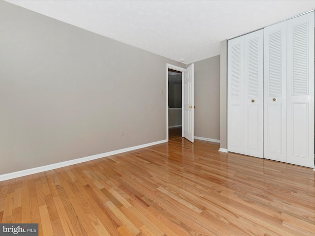 unfurnished bedroom with a closet, light wood-style flooring, and baseboards