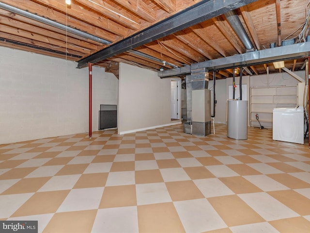 unfinished below grade area with heating unit, washer / dryer, gas water heater, and tile patterned floors