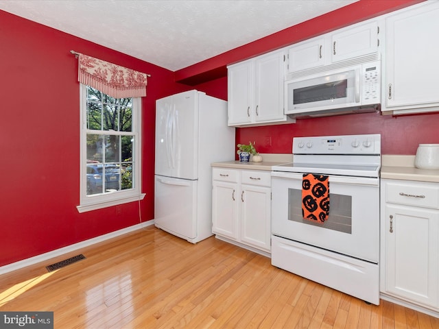 kitchen with light countertops, white appliances, visible vents, and white cabinetry