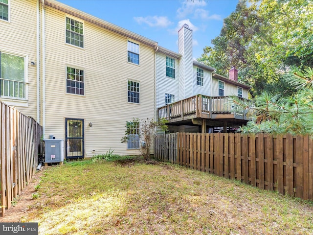 rear view of property with central AC, fence, and a chimney