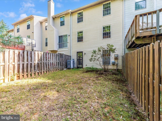 rear view of property with fence, a chimney, and central AC unit