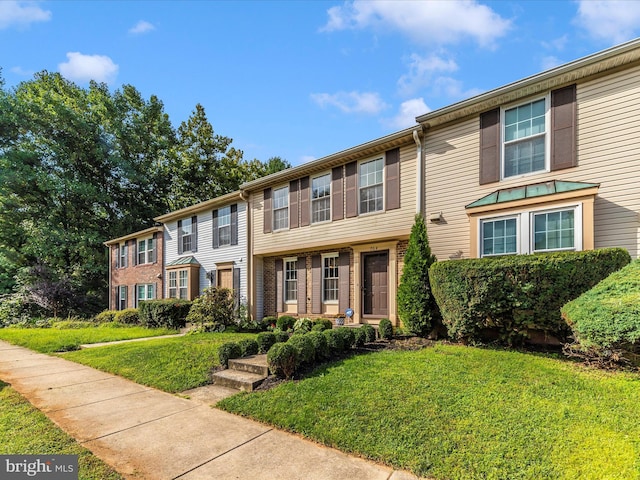 townhome / multi-family property with a front lawn and brick siding