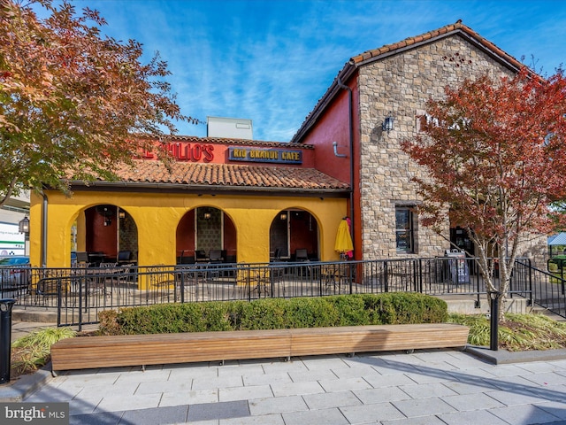 view of front of property with stone siding, a tiled roof, and stucco siding