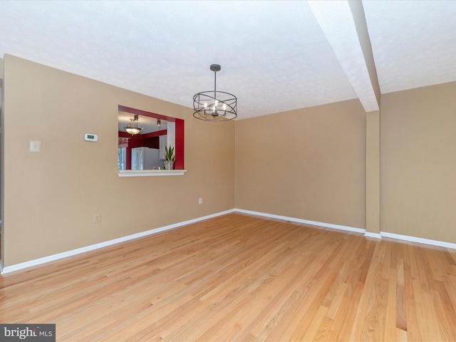 unfurnished dining area featuring an inviting chandelier, light wood-style flooring, and baseboards