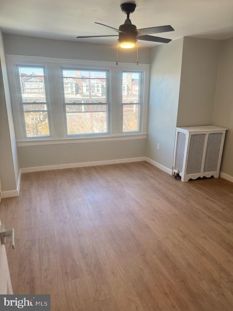 empty room featuring ceiling fan, baseboards, and wood finished floors