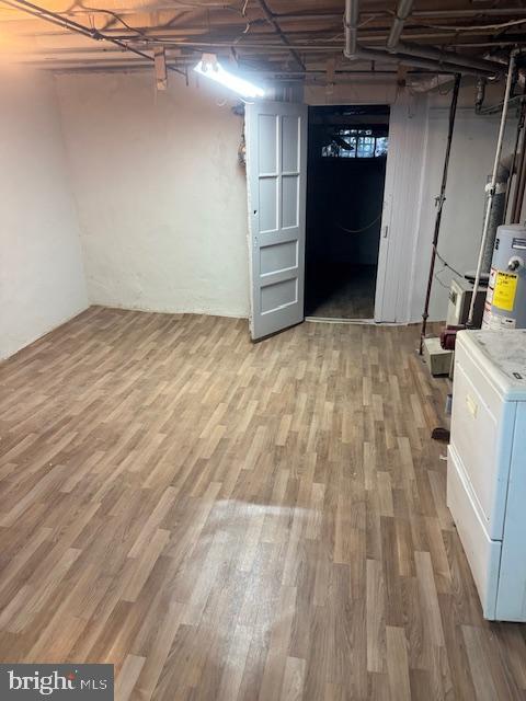 unfinished basement featuring water heater, washer / clothes dryer, and light wood-style flooring