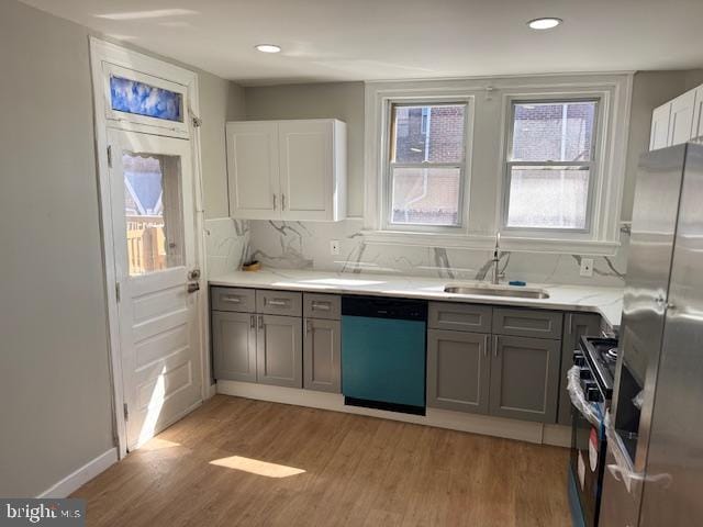 kitchen featuring a sink, appliances with stainless steel finishes, light wood-type flooring, gray cabinets, and tasteful backsplash