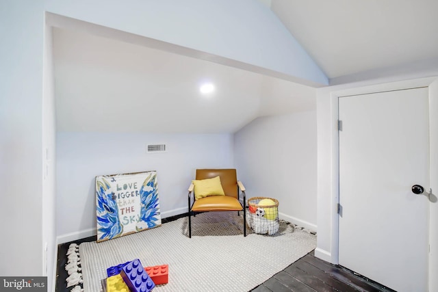 living area featuring dark wood finished floors, visible vents, vaulted ceiling, and baseboards