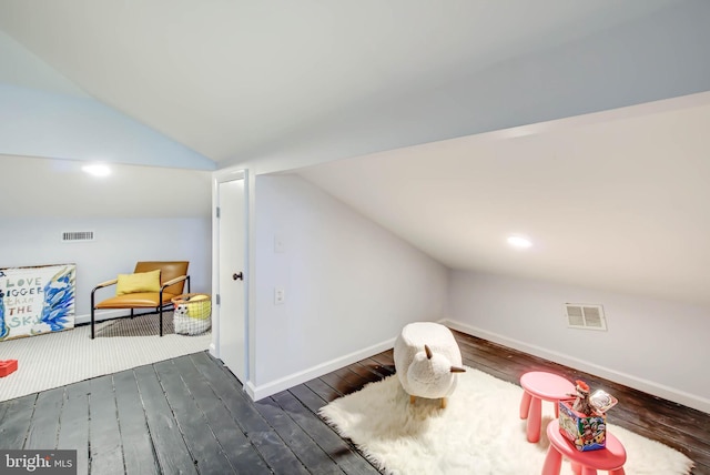 interior space with vaulted ceiling, dark wood finished floors, visible vents, and baseboards