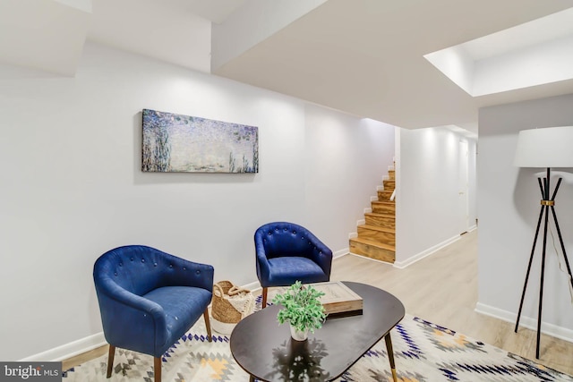 sitting room featuring stairs, baseboards, and wood finished floors