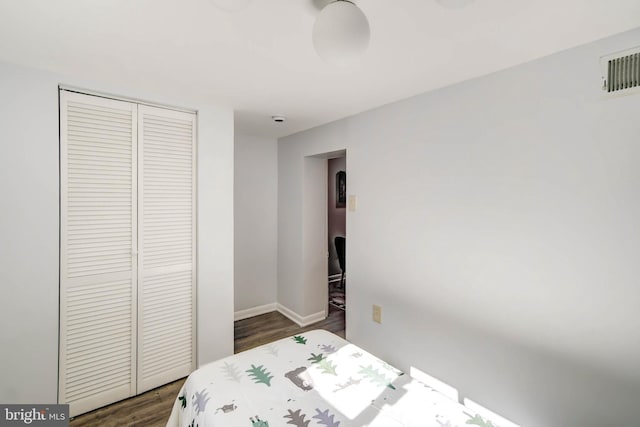 bedroom with dark wood-style floors, a closet, visible vents, and baseboards