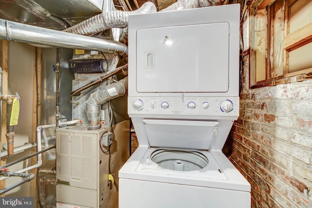 washroom with laundry area, brick wall, and stacked washer / drying machine