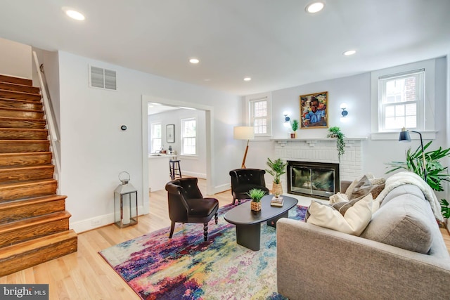 living area with a healthy amount of sunlight, stairs, visible vents, and wood finished floors