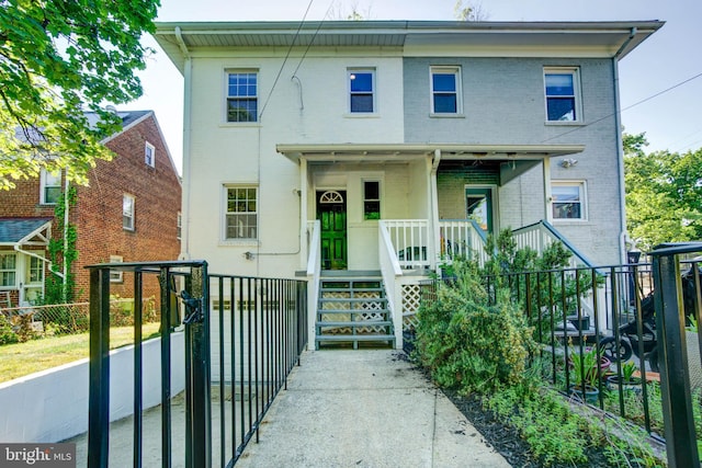 view of front of house with covered porch, brick siding, and fence