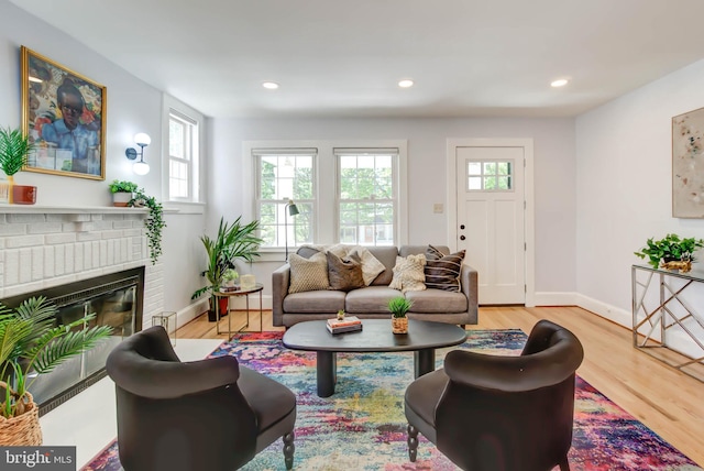 living area featuring recessed lighting, a fireplace, baseboards, and wood finished floors