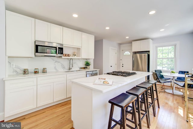 kitchen featuring stainless steel appliances, light wood finished floors, a sink, and white cabinets