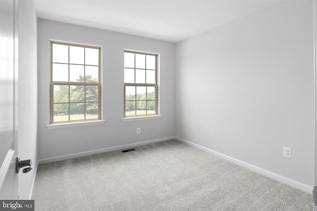 carpeted spare room featuring visible vents and baseboards