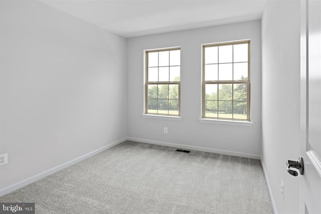 carpeted empty room featuring baseboards and visible vents