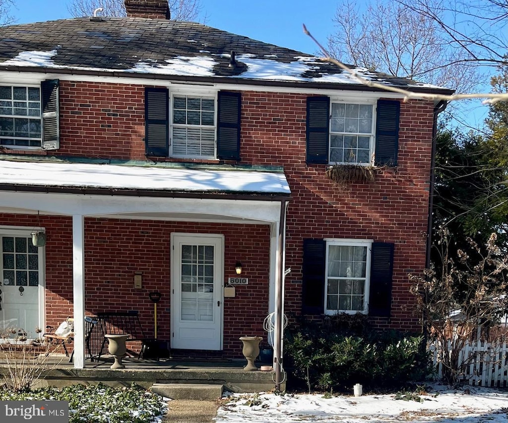 view of front facade with brick siding and a chimney