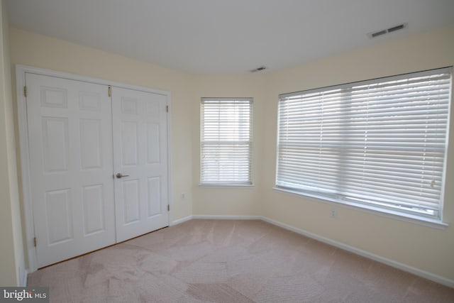 unfurnished bedroom with baseboards, a closet, visible vents, and carpet flooring