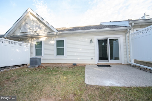 rear view of property featuring central air condition unit, a patio area, fence, and a lawn