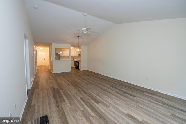 unfurnished living room featuring vaulted ceiling, wood finished floors, a ceiling fan, and baseboards