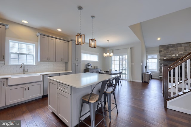 kitchen featuring a notable chandelier, dark wood-type flooring, a sink, a kitchen breakfast bar, and backsplash