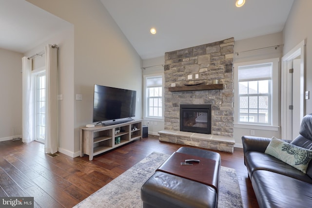 living area featuring lofted ceiling, wood finished floors, recessed lighting, a stone fireplace, and baseboards