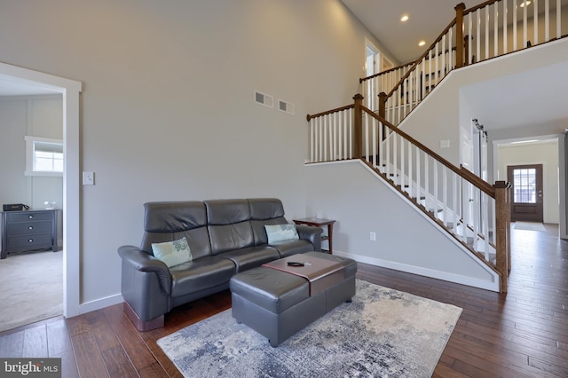 living area featuring a wealth of natural light, visible vents, stairs, and wood-type flooring