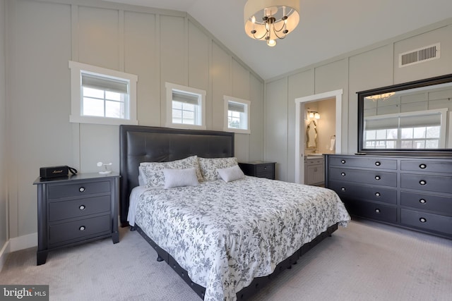 bedroom featuring visible vents, vaulted ceiling, light carpet, a decorative wall, and multiple windows