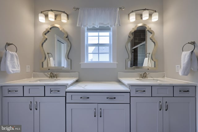 full bathroom with a tile shower, two vanities, and a sink