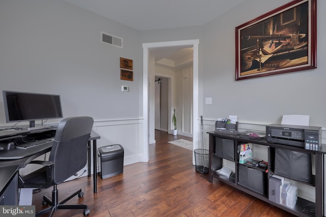 home office with visible vents, wainscoting, and wood finished floors