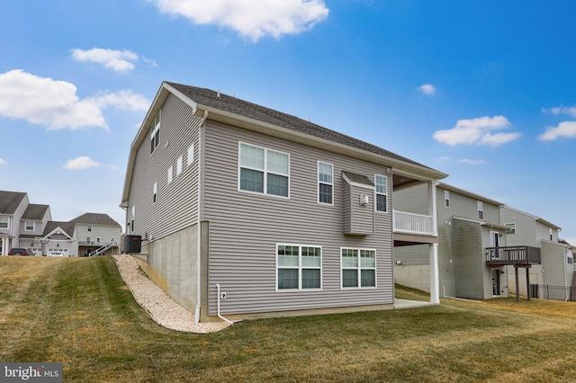 rear view of house featuring central air condition unit and a yard