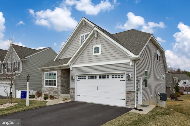 craftsman house featuring aphalt driveway, stone siding, and roof with shingles