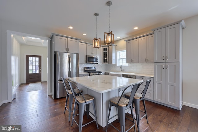 kitchen with a kitchen bar, a kitchen island, dark wood finished floors, stainless steel appliances, and glass insert cabinets