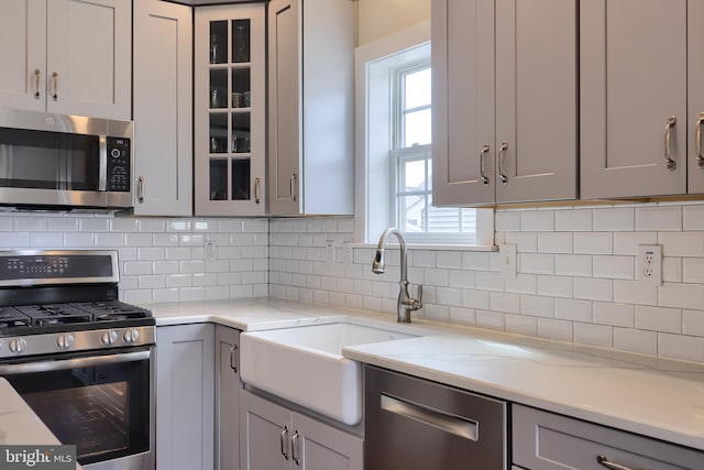 kitchen with decorative backsplash, appliances with stainless steel finishes, and gray cabinetry